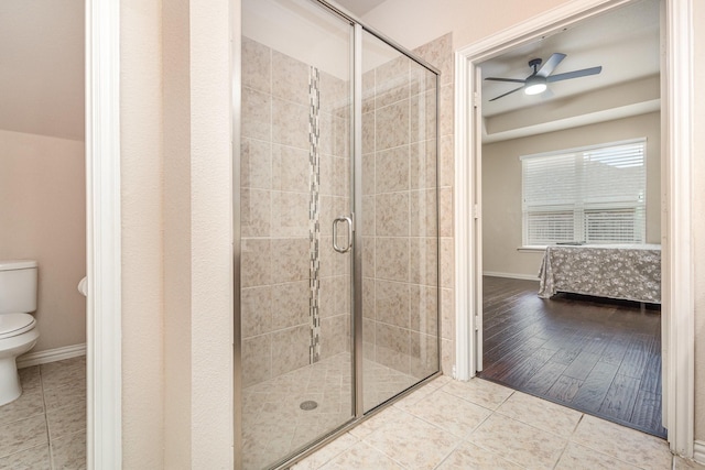 bathroom featuring ceiling fan, toilet, an enclosed shower, and tile patterned flooring