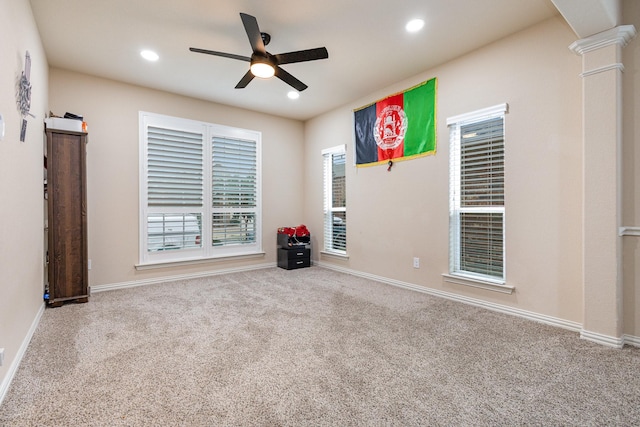 carpeted spare room featuring ceiling fan and ornate columns