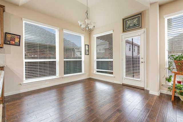 unfurnished dining area featuring dark wood-type flooring and a notable chandelier