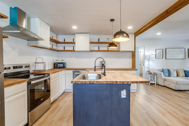 kitchen featuring white cabinetry, sink, stainless steel range with electric cooktop, hanging light fixtures, and wall chimney exhaust hood