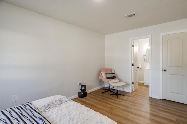 bedroom with hardwood / wood-style floors and ensuite bathroom