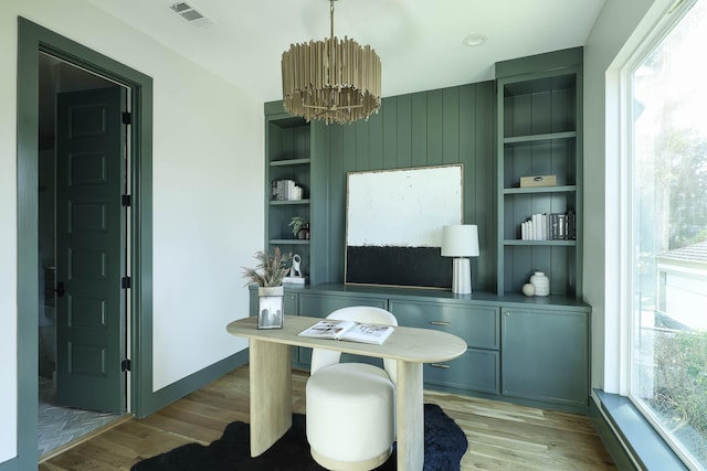 office area featuring built in features, a chandelier, and light wood-type flooring