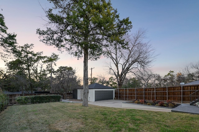 yard at dusk featuring an outbuilding and a garage