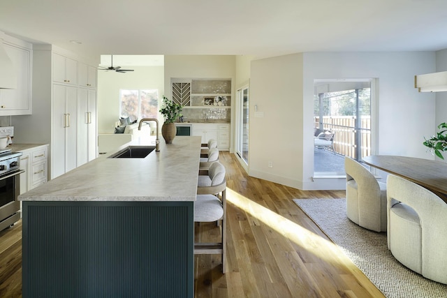 kitchen featuring white cabinetry, sink, a kitchen island with sink, and a kitchen breakfast bar