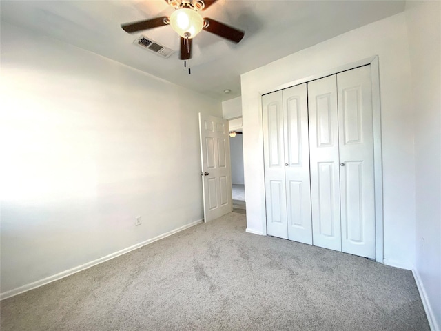 unfurnished bedroom featuring light colored carpet, a closet, and ceiling fan