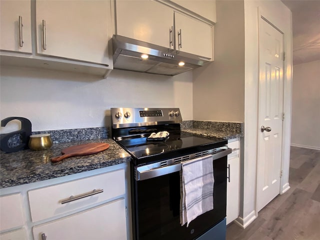 kitchen with dark wood-type flooring, dark stone countertops, white cabinets, and stainless steel range with electric stovetop