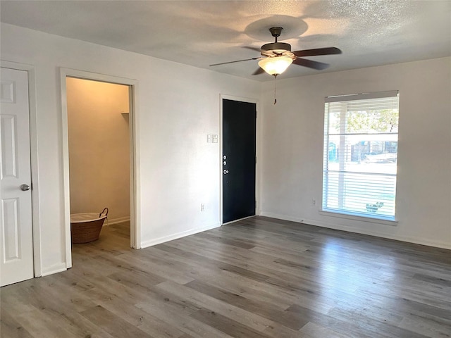 unfurnished room with ceiling fan, dark hardwood / wood-style floors, and a textured ceiling