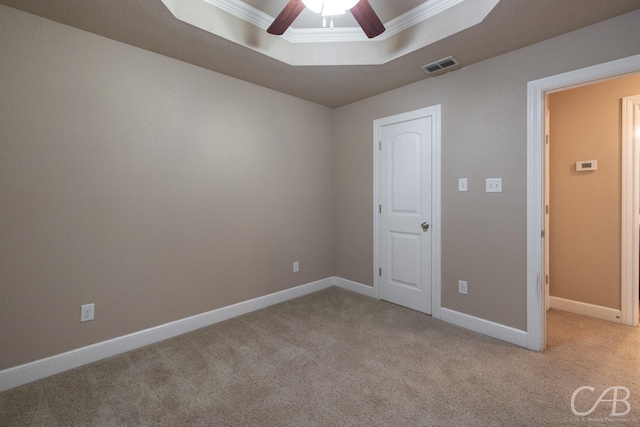 carpeted empty room with crown molding, ceiling fan, and a raised ceiling