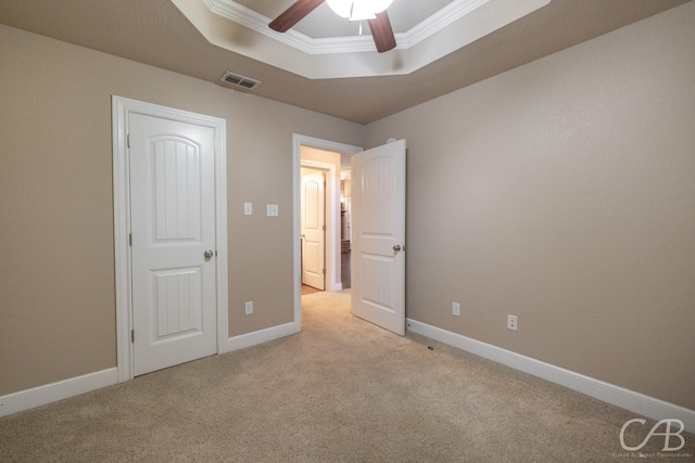 unfurnished bedroom featuring crown molding, light colored carpet, a tray ceiling, and ceiling fan