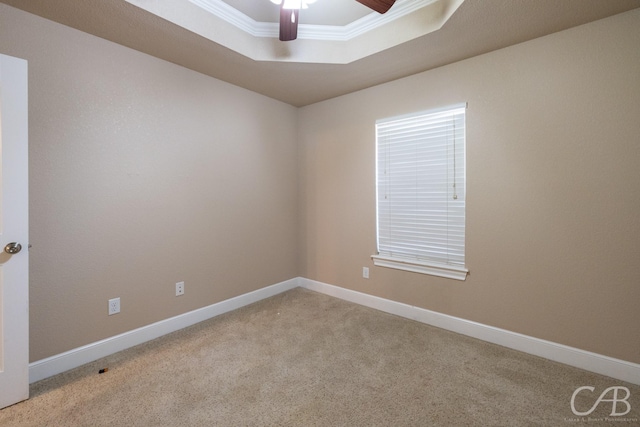 carpeted empty room with a raised ceiling, ornamental molding, and ceiling fan