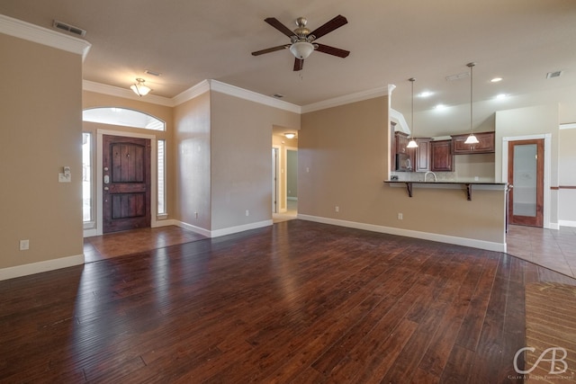 unfurnished living room featuring sink, crown molding, dark wood-type flooring, and ceiling fan