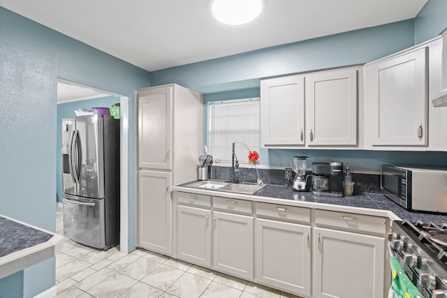 kitchen featuring ornamental molding, appliances with stainless steel finishes, sink, and white cabinets