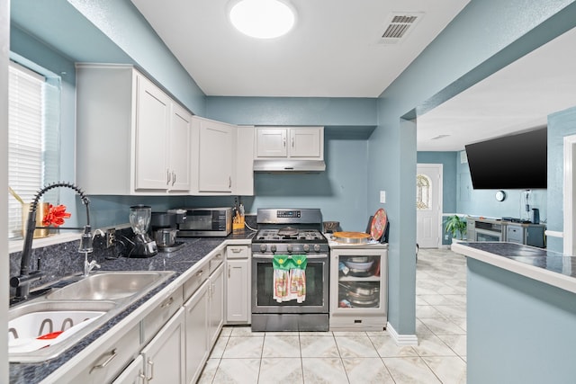 kitchen with light tile patterned floors, sink, gas stove, and white cabinets