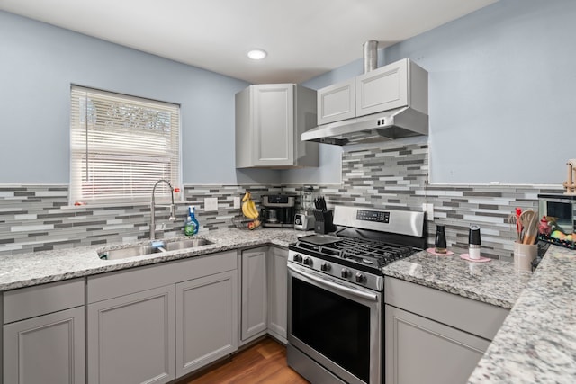 kitchen with stainless steel gas stove, sink, light stone counters, and gray cabinets