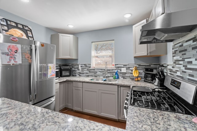 kitchen featuring sink, backsplash, stainless steel appliances, extractor fan, and light stone countertops