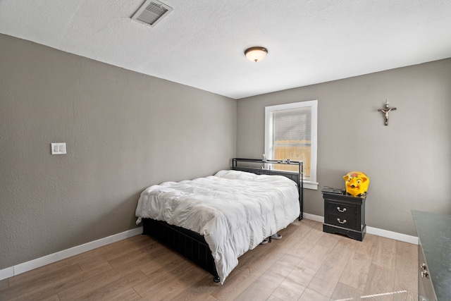 bedroom with a textured ceiling and light wood-type flooring