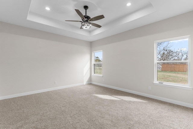 carpeted spare room with ceiling fan and a raised ceiling