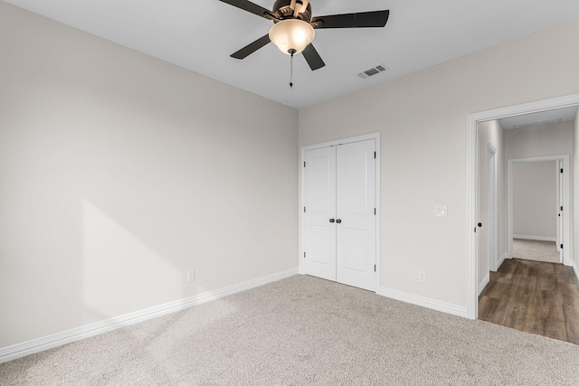 unfurnished bedroom featuring dark colored carpet, ceiling fan, and a closet