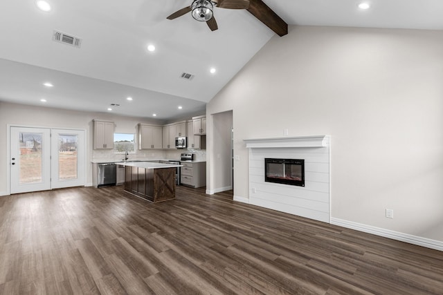 kitchen featuring appliances with stainless steel finishes, beam ceiling, a kitchen breakfast bar, a kitchen island, and dark hardwood / wood-style flooring