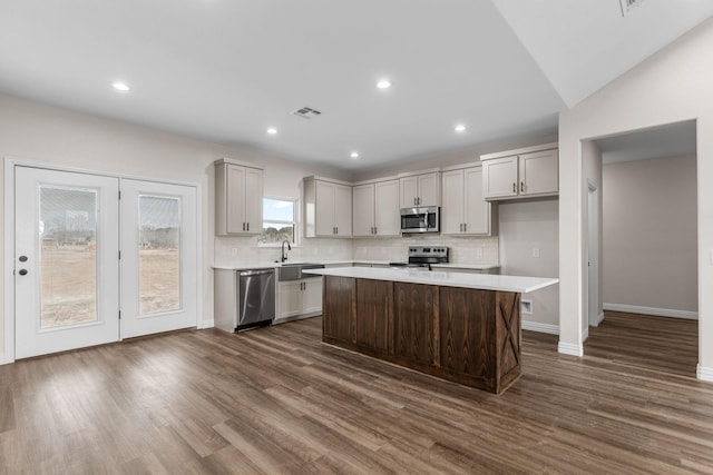 kitchen featuring appliances with stainless steel finishes, dark hardwood / wood-style flooring, a center island, and sink