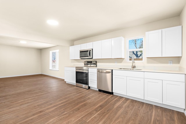 kitchen with appliances with stainless steel finishes, sink, white cabinets, and dark hardwood / wood-style flooring