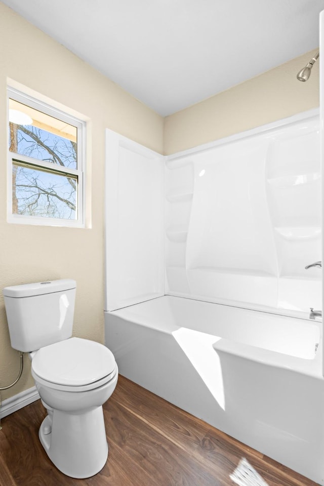 bathroom with wood-type flooring, tub / shower combination, and toilet