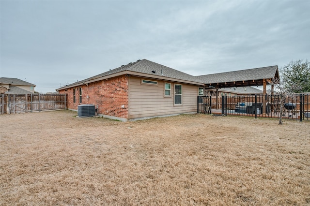 rear view of house featuring central AC and a lawn