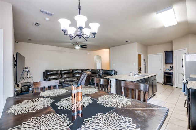 tiled dining space with ceiling fan with notable chandelier and sink