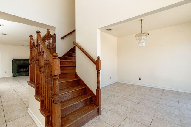 stairs with an inviting chandelier, a fireplace, and tile patterned flooring