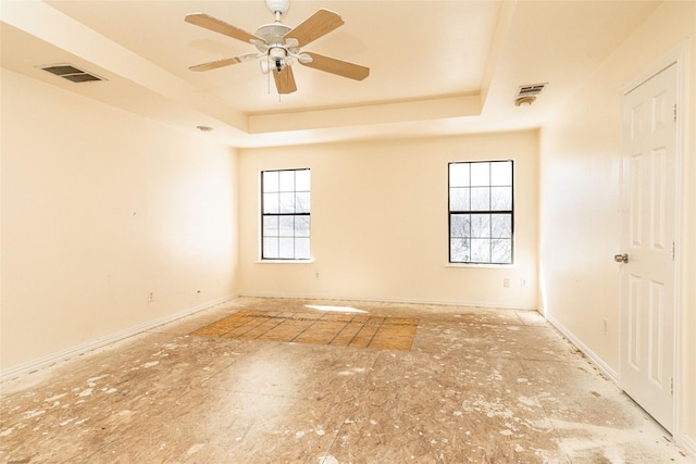 spare room with ceiling fan and a raised ceiling