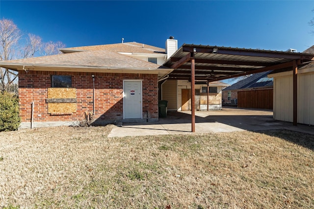 back of house featuring a carport and a lawn