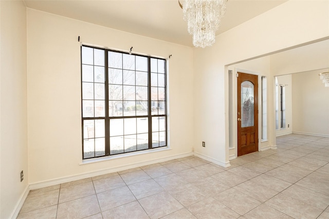 spare room with a notable chandelier, plenty of natural light, and light tile patterned flooring