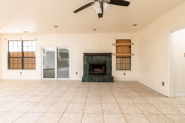 unfurnished living room with a tile fireplace, light tile patterned floors, and ceiling fan