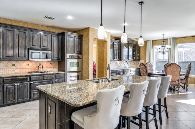 kitchen featuring pendant lighting, sink, a breakfast bar area, a kitchen island with sink, and stainless steel appliances