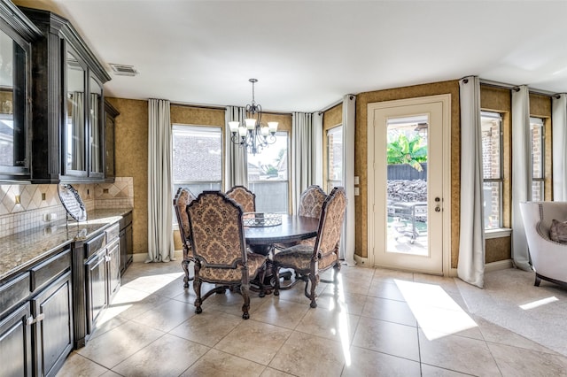 tiled dining room featuring an inviting chandelier and plenty of natural light