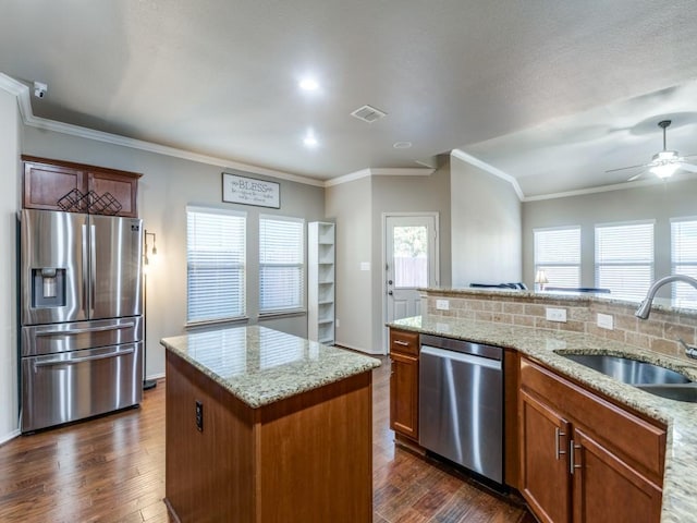 kitchen featuring sink, dark wood-type flooring, appliances with stainless steel finishes, light stone counters, and a kitchen island