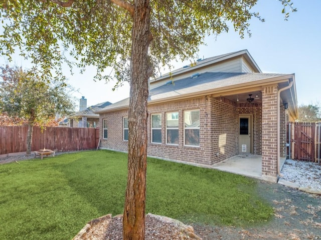 rear view of property featuring ceiling fan, a patio, and a lawn