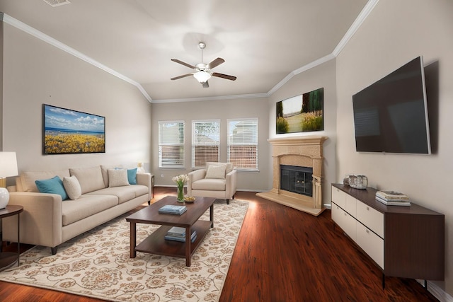 living area with a glass covered fireplace, wood finished floors, a ceiling fan, and crown molding