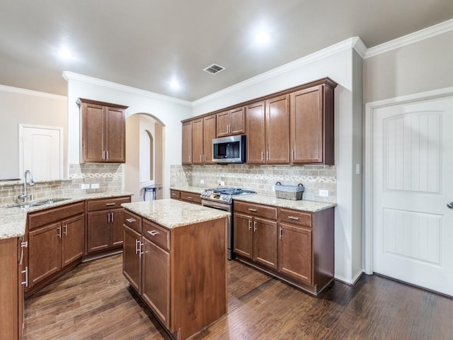 kitchen featuring appliances with stainless steel finishes, dark hardwood / wood-style floors, sink, a center island, and light stone countertops