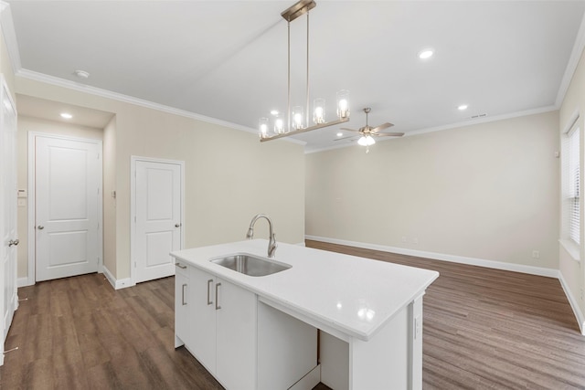 kitchen featuring a center island with sink, ornamental molding, sink, and pendant lighting