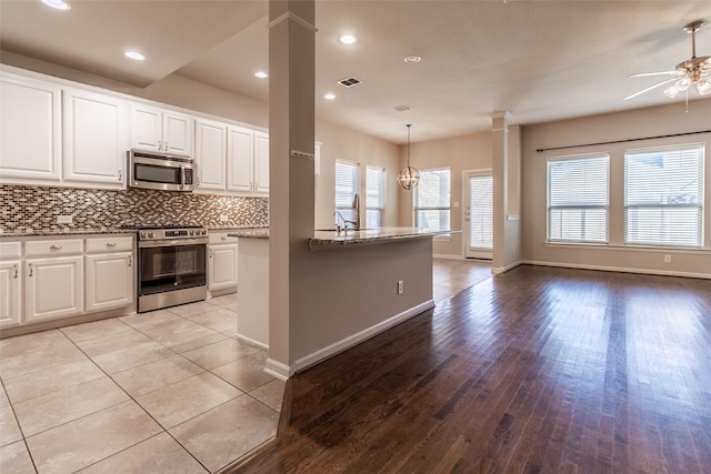 kitchen with white cabinetry, appliances with stainless steel finishes, decorative columns, and hanging light fixtures