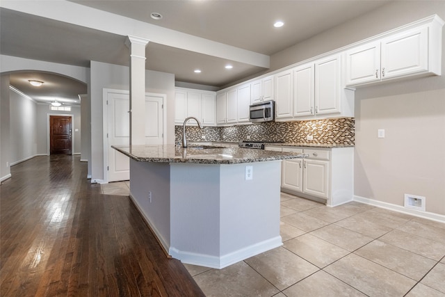 kitchen with white cabinetry, sink, and a center island with sink