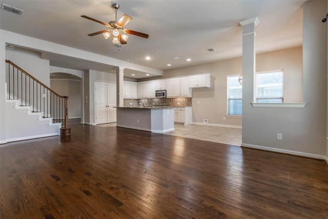 unfurnished living room featuring ceiling fan, hardwood / wood-style floors, and ornate columns