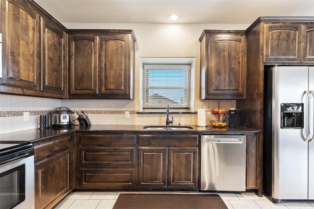 kitchen with light tile patterned flooring, tasteful backsplash, sink, dark brown cabinetry, and stainless steel appliances