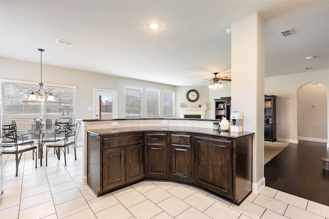 kitchen featuring pendant lighting, dark brown cabinets, kitchen peninsula, and a healthy amount of sunlight