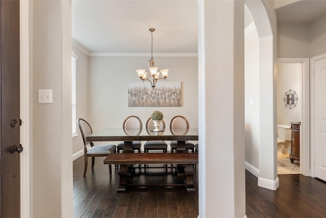 dining area featuring dark hardwood / wood-style flooring, crown molding, and a chandelier