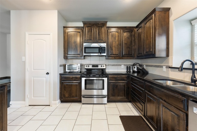 kitchen with sink, light tile patterned floors, dark brown cabinets, stainless steel appliances, and tasteful backsplash