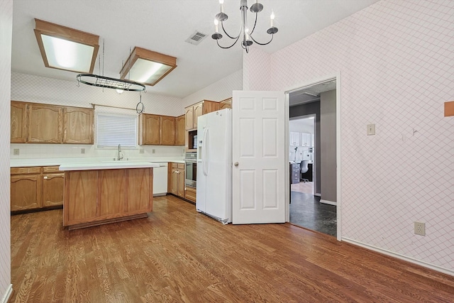 kitchen with dark hardwood / wood-style flooring, a kitchen island, pendant lighting, and white appliances