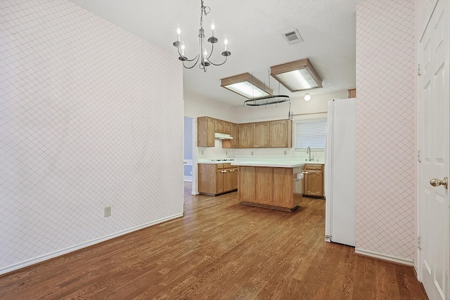 kitchen featuring sink, a center island, dark hardwood / wood-style flooring, white fridge, and pendant lighting