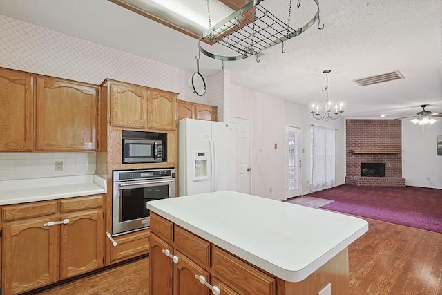 kitchen featuring a kitchen island, wood-type flooring, oven, hanging light fixtures, and white fridge with ice dispenser